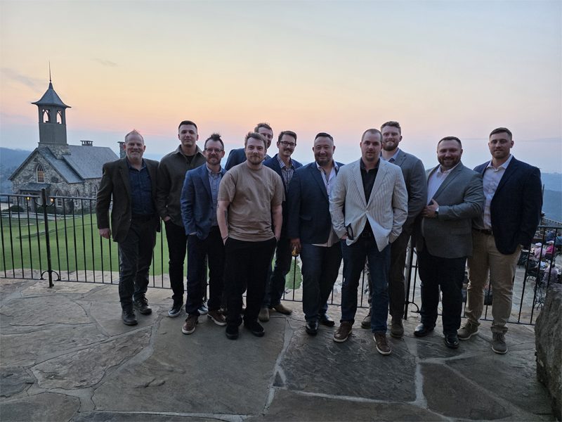A Gold cohort gathered at sunset on a stone terrace overlooking a valley chapel